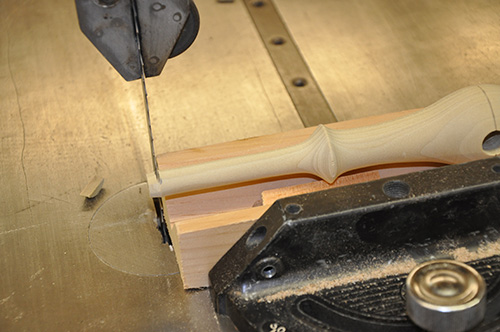 Cutting away extra wood from footstool stretcher with bandsaw