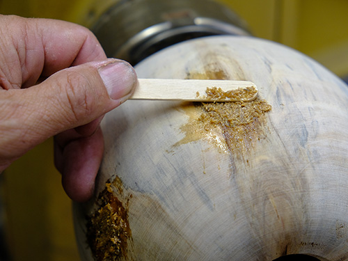 Spreading epoxy and sawdust mixture on turning blank