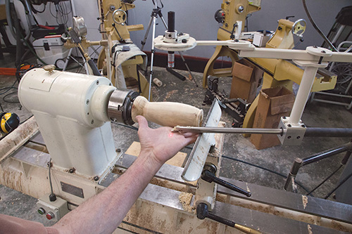 Checking the adjustment on a laster beam attached to a lathe