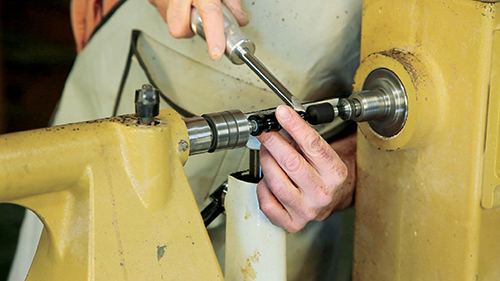 Using a live center in the tailstock to support your tap holder will ensure the thread is on an axis with the hole. As you turn the finial between centers, catch the nut with the tailstock’s live center.