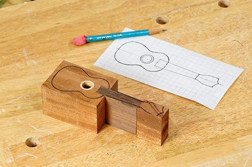 Once the uke ornament log is glued up and the top and bottom faces are sanded flat, a paper pattern of the uke’s outside profile is drawn on, in preparation for cutting the log to shape.