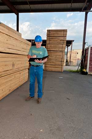 Clipboard Guy In Front of Stacked Wood