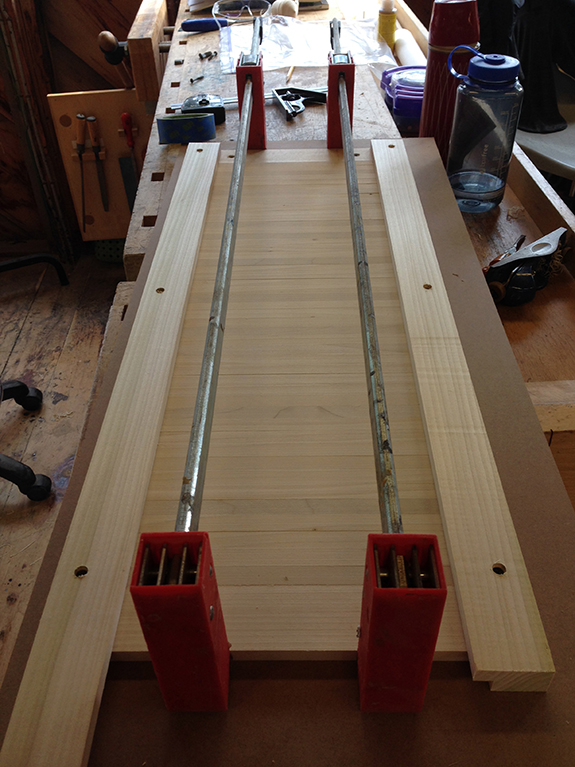 A tambour door consists of slats that are held together by cloth (usually canvas). It is important to glue the tambour slats parallel to each other, so we used a jig.
