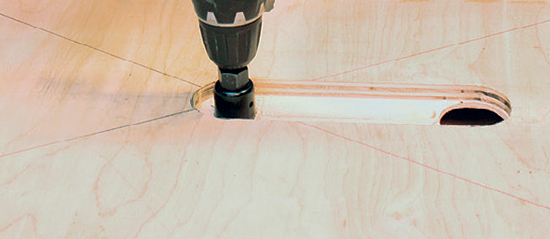 Cut a large access hole for a shop vacuum dust port into one end of the dust chamber, and bore a second smaller hole to fit your router’s collet into the other end of the chamber. A pair of hole saws and a drill make this easy work.