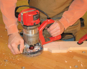 Figure 5. Using a handheld router with a 45-degree chamfer bit in the chuck, shape the bottom forward edge of the rail (the same face with the holes drilled for the pegs). Don't shape the long straight top edge.